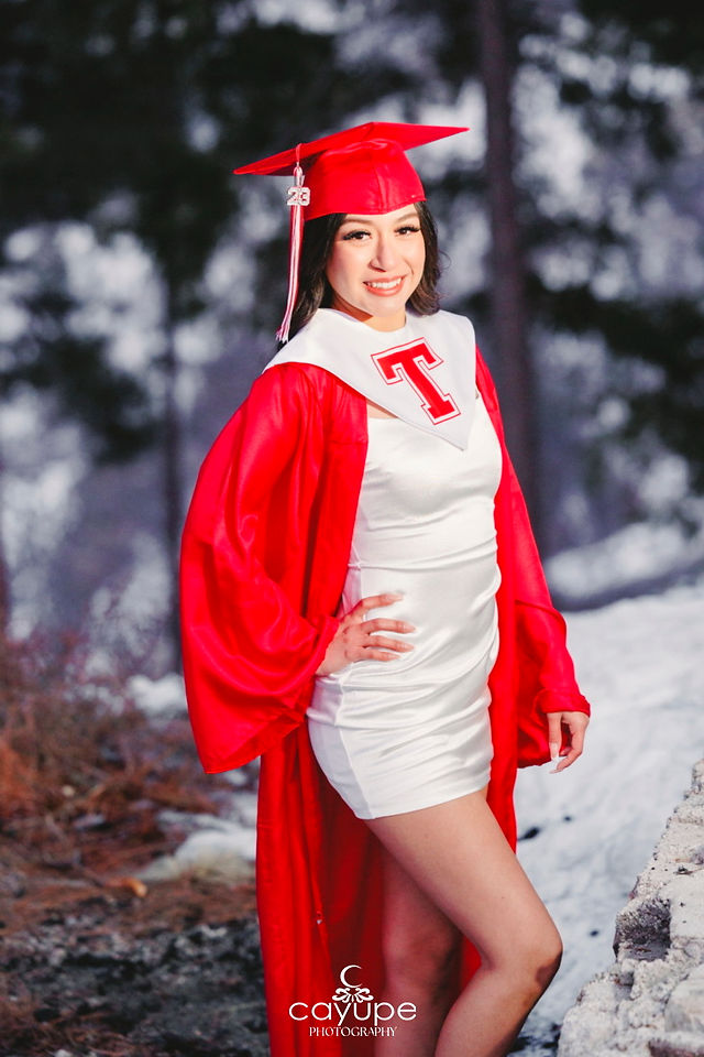 1.	Jasmin wearing her red graduation cap and gown, standing in the snow with a confident smile and a blurred forest background. 