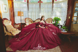 Luciana reclines on a vintage sofa, burgundy gown fanned beneath stained glass bay windows in Kingan Gardens.
