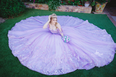 Princess-style portrait of Kayla sitting with her dress arranged in a perfect circle, holding her bouquet and softly adjusting her crown.