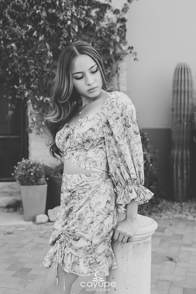 Brenda in profile next to a cactus, wearing a textured pink dress with a thoughtful expression.