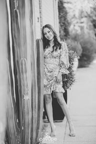 Black and white portrait of Brenda smiling while posing next to a cactus.