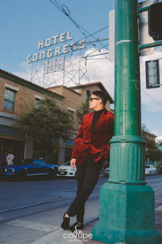 •	Sunglasses on, Christian relaxes by the streetlight as the Hotel Congress neon towers overhead, blending bold fashion with Tucson’s skyline.