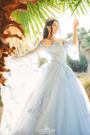 Dezeray with an elegant expression and her hands raised, highlighting the sparkling details of her dress.