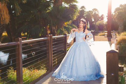 Dezeray posing on the bridge with her hands on her waist, highlighting her quinceañera dress in a natural setting.