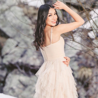 Jasmin posing elegantly in her cream gown with a playful smile, turning slightly and showcasing her soft curls.