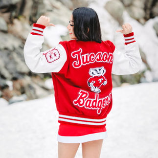 10. Jasmin showing off the back of her cheer jacket with "Tucson Badgers" embroidered, standing in a snowy setting.