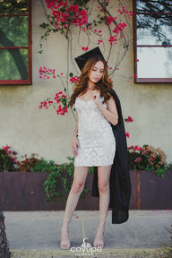 Brenda in profile with a black gown, wearing a white dress, and a rustic background.
