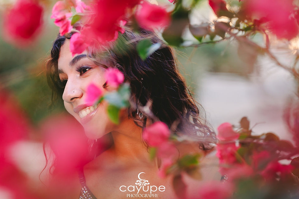 Intimate portrait of Alondra’s face framed by soft focus bougainvillea petals, capturing her radiant smile during this Tucson senior session.