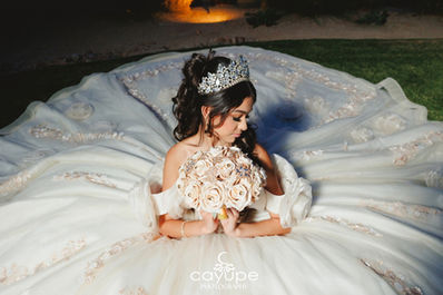 Evening shot of Brianna seated on grass, her dress fanned out in a perfect circle while she cradles a blush rose bouquet at Omni Tucson National Resort.