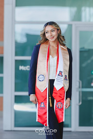 Cassandra standing proudly in front of Eller’s main doors, showcasing her graduation stoles from the University of Arizona.