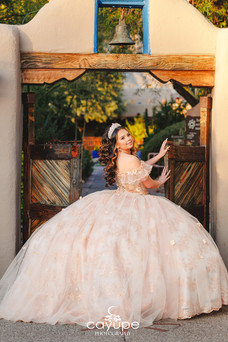 Quinceanera posing in front of rustic wooden doors at a hacienda in Tucson.