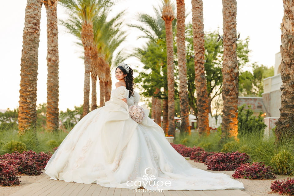 Rear view of Brianna’s flowing gown and bow as she glances over her shoulder along the palm avenue at Omni Tucson National Resort.