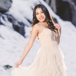 Jasmin in her gown, standing confidently in the snow with the sunlight softly illuminating her face