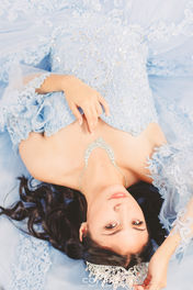Dezeray lying down with her blue dress spread out like a fan, highlighting her elegance and unique style.