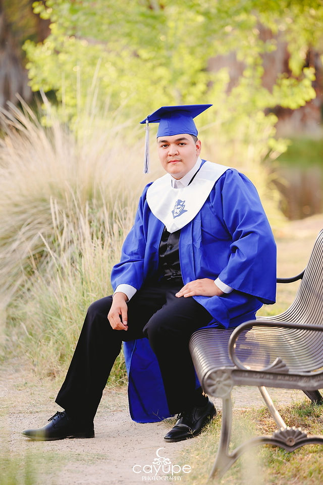 Gerardo in his blue gown and cap, sitting on a bench at Agua Caliente.