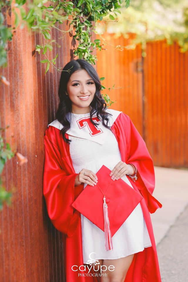 Kristal wearing her red graduation gown from Tucson High School, holding her cap. 