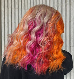 Wavy blonde, pink, and orange hair, vibrant style, hair salon in Greenville SC.