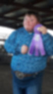 Young man holding purple ribbon at fair livestock show