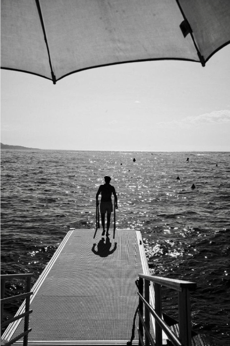 Silhouette of a person on crutches by the sea.