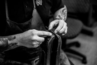 Ein Sattler von Otto Schumacher beim anfertigen eines Halsbandes aus Leder für Hunde