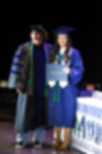 Graduate receiving diploma for student success ceremony.