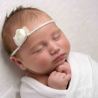 sleeping baby wrapped in white with flower headband