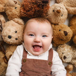 smiling baby surrounded by teddy bears