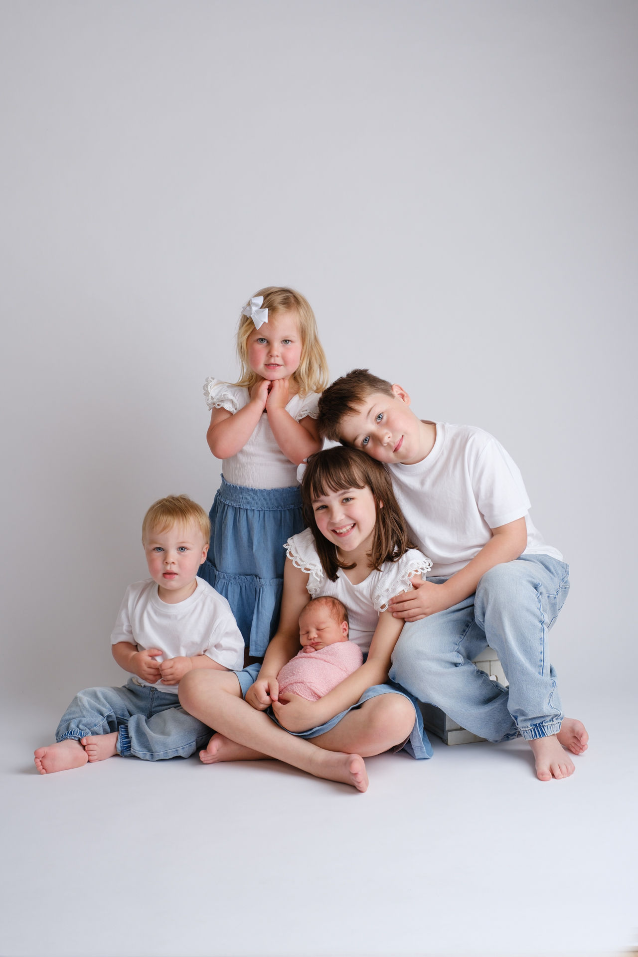 brothers an sisters hold their newborn sibling