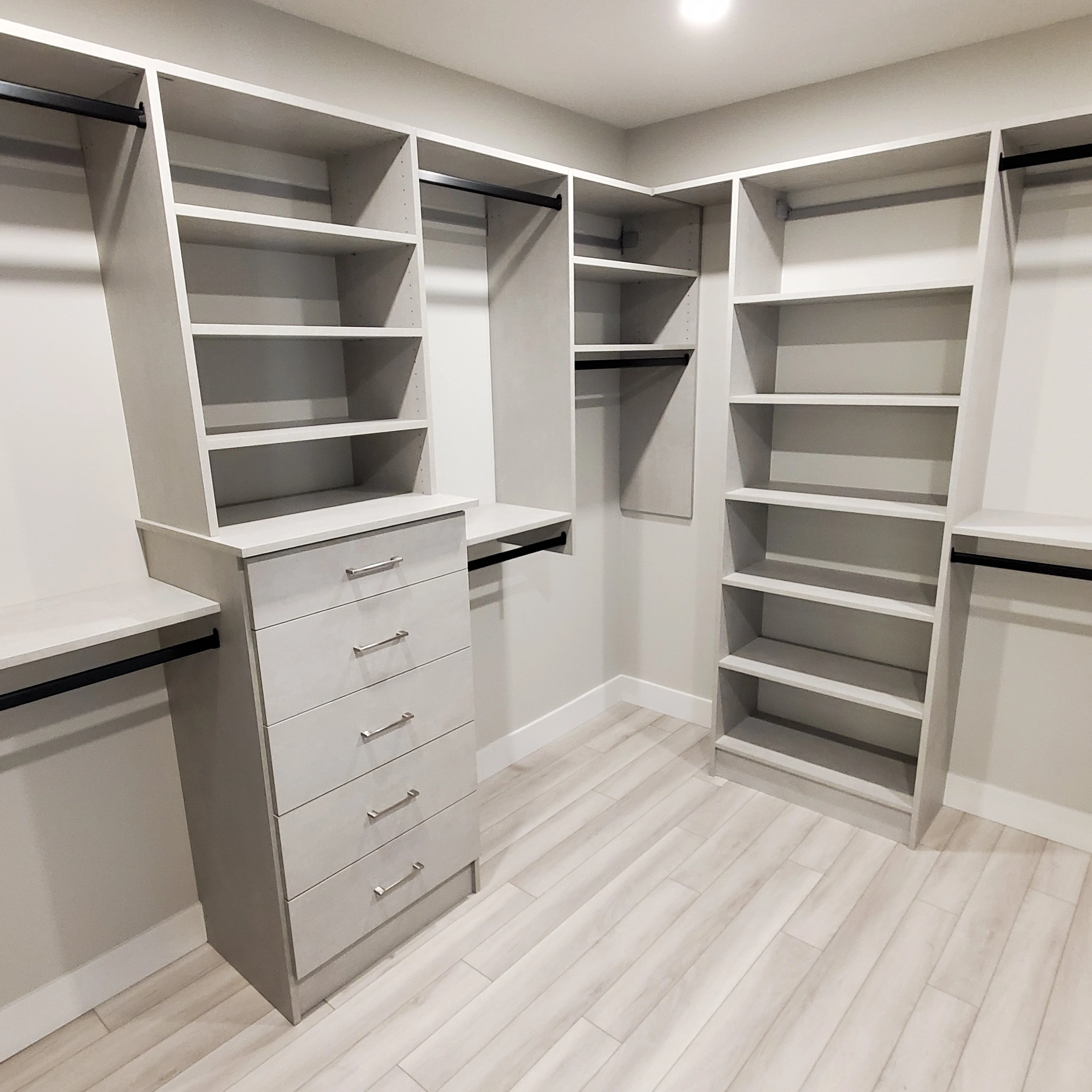 Grey wood grain custom walk-in closet organizing system with drawers and open shelving by Calgary Custom Closets