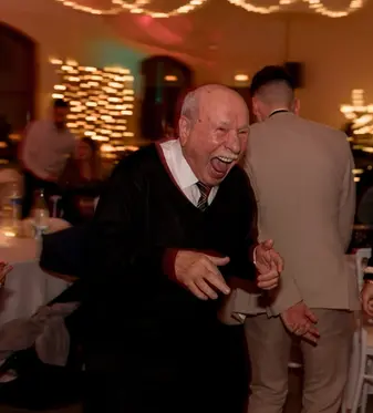 photographie d'une personne âgé homme qui danse pendant un mariage en hiver à la rochelle en intérieur, il rigole beaucoup