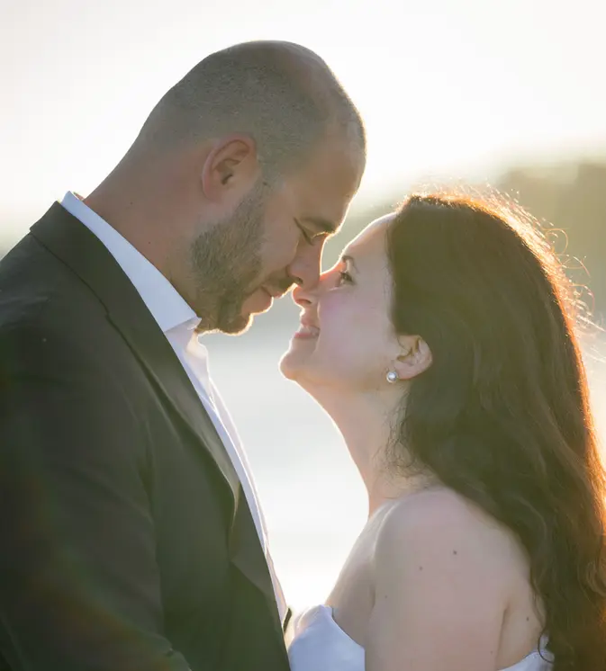 photo d'un couple de marié à la rochelle sous un joli levé de soleil sur la plage. elle est en robe de mariée et lui en costume de marié. ils se regardent front contre front