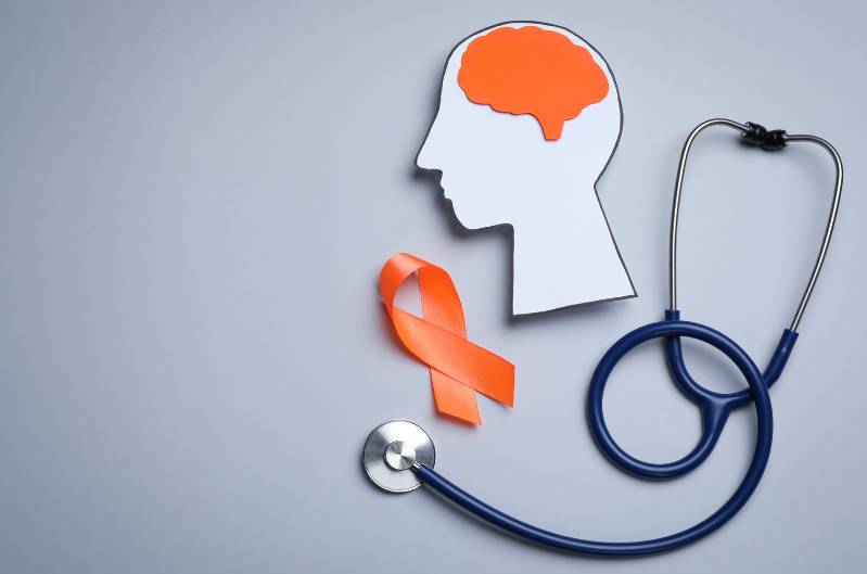 A human head cutout, orange ribbon and a stethoscope to represent multiple sclerosis awareness