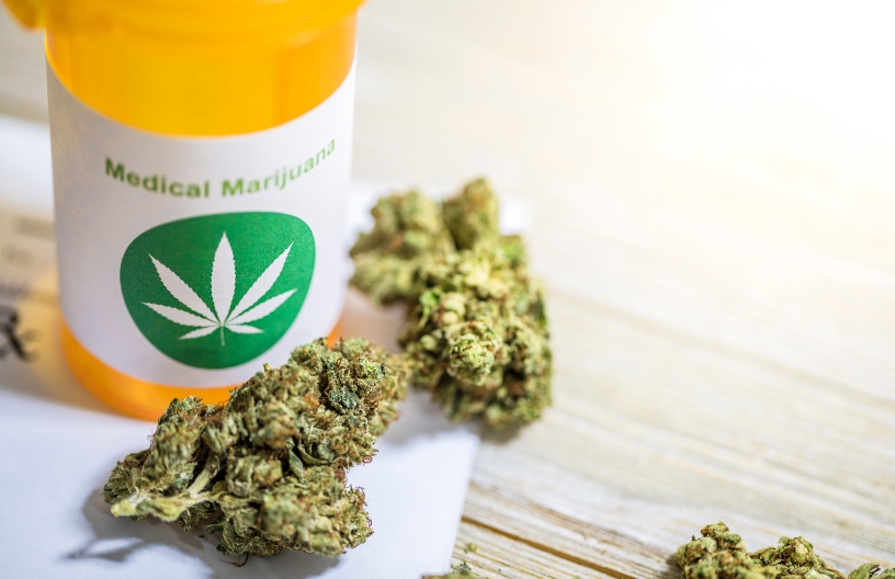 A prescription bottle with a label that says medical marijuana beside marijuana flower