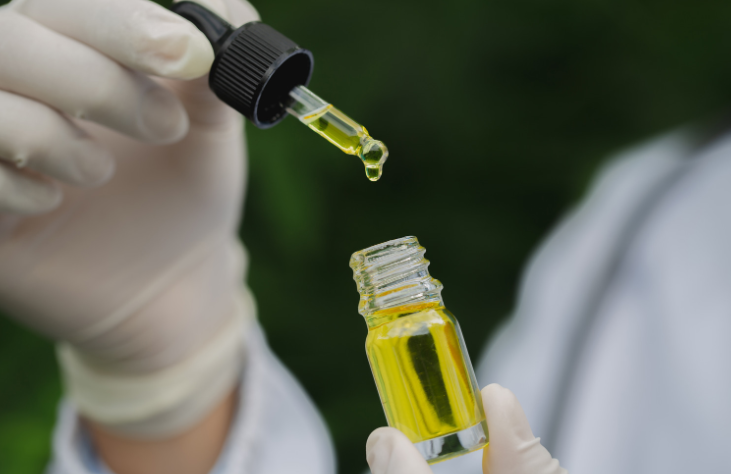 CBD cannabis oil extract dropping from a dropper into a bottle of cannabis oil