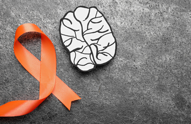 A paper cutout of a brain and an orange ribbon representing multiple sclerosis