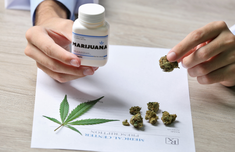 A doctor holding a bottle of medical marijuana with loose cannabis flower on a prescription pad