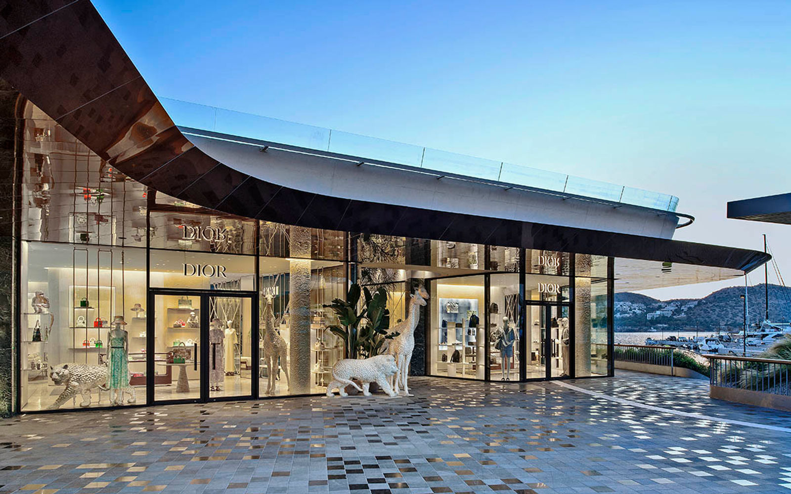 The Dior boutique at Astir Marina, a low glass pavilion under a dark curved roof.