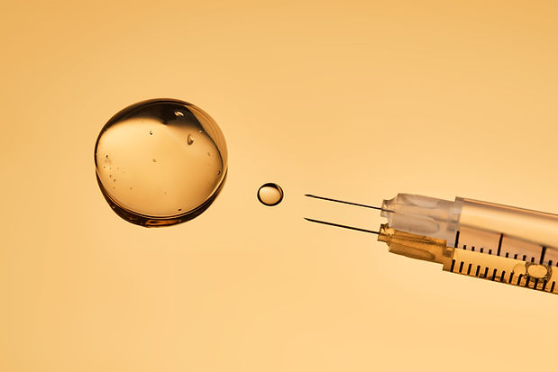 A drop of gel pours from a syringe for cosmetic procedures.jpg