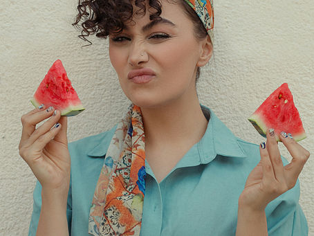 A woman holding slices of watermelon