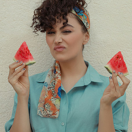 A woman holding slices of watermelon