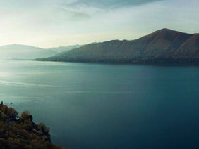 Blue lake water with mountains in the far distance and on either side