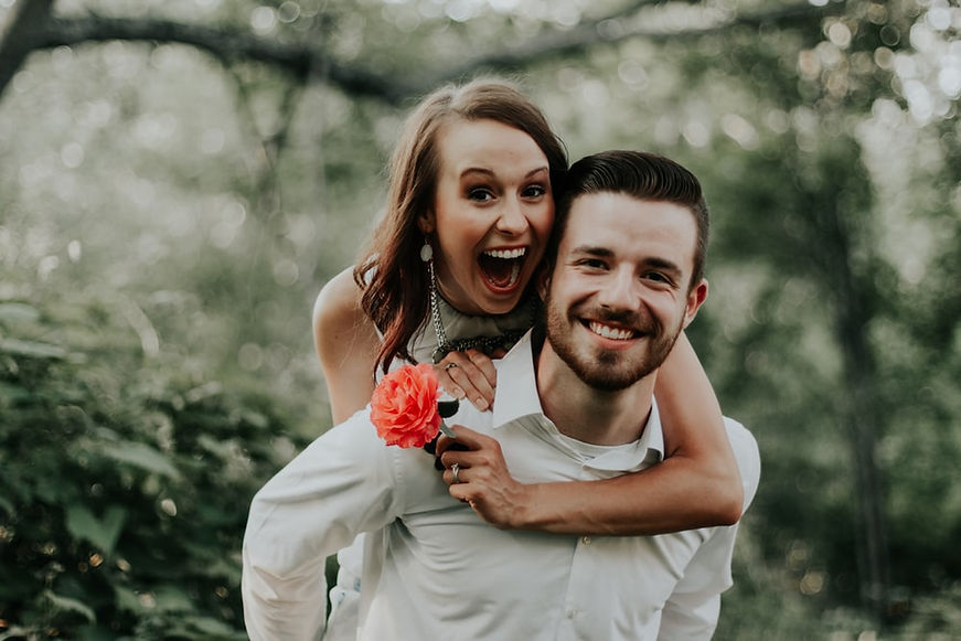 Smiling man giving woman a piggyback ride outdoors.
