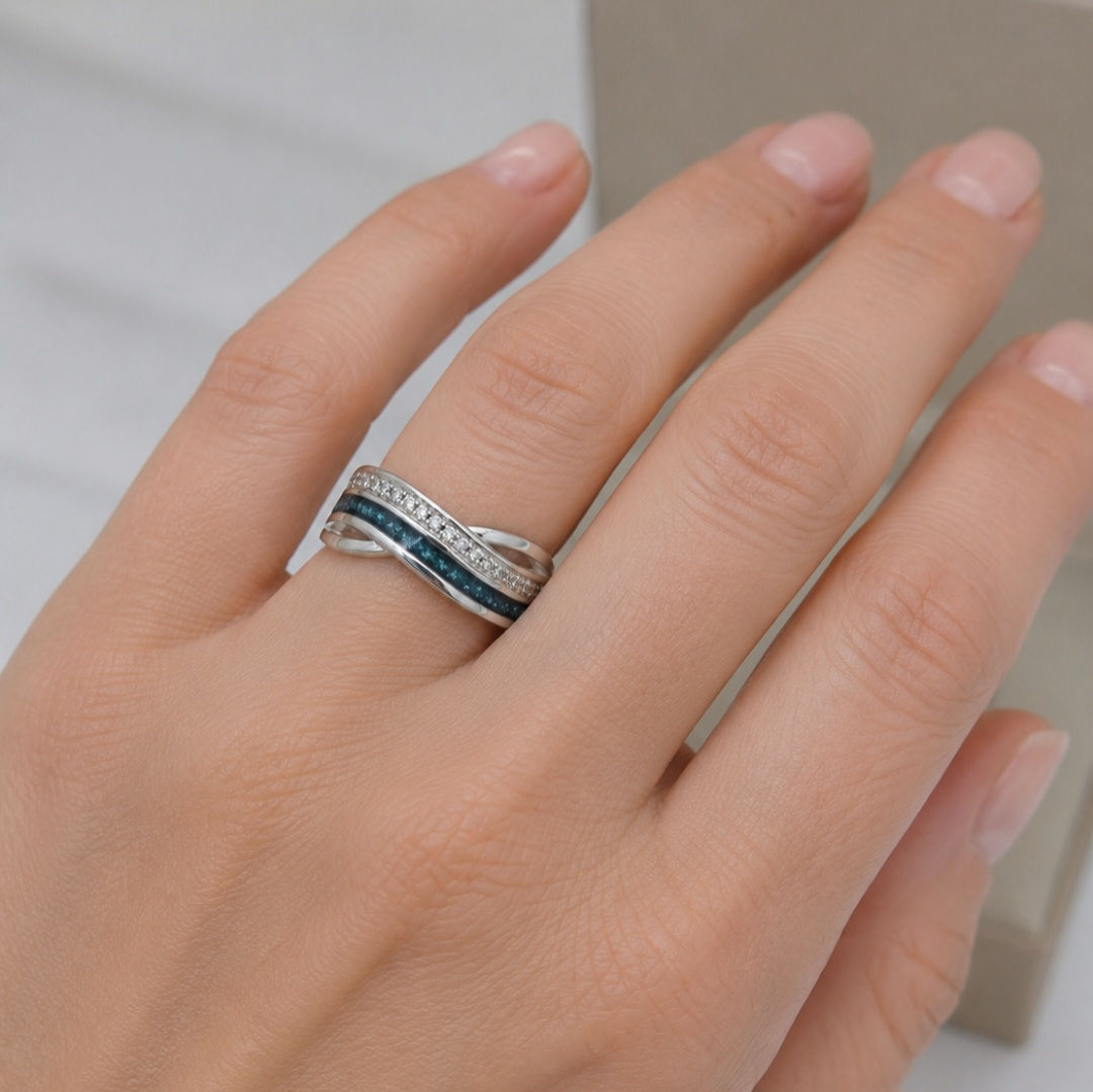 A woman's hand wearing a handmade Sterling Silver wave memorial ring set with cremation ashes