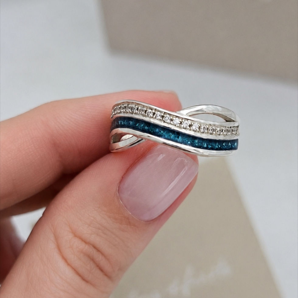 Thumbnail: Woman's hand holding a handmade sterling silver memorial ring with cremation ashes