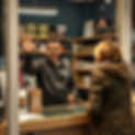 Locksmith shop keeper standing behind counter waving customer into store.jpg