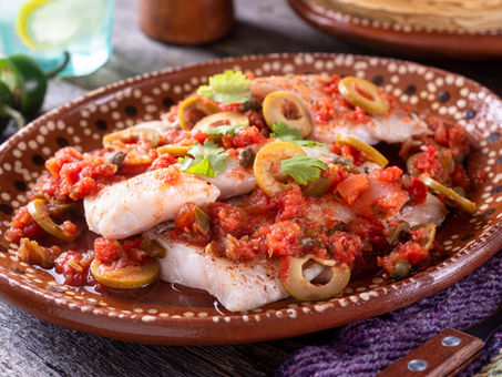 Pescado a la veracruzana servido con salsa de jitomate, aceitunas y alcaparras, una receta tradicional mexicana de Cuaresma preparada con filete de pescado blanco.
