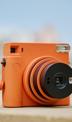 Vintage Orange Instant Camera in city with cloudy sky_edited.jpg