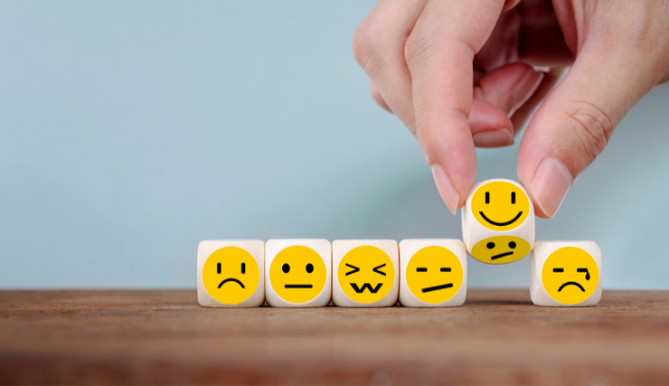 Dice with emojis in a row with a hand placing one down on the table