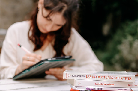 femme qui écrit avec des livres autour, concentrée