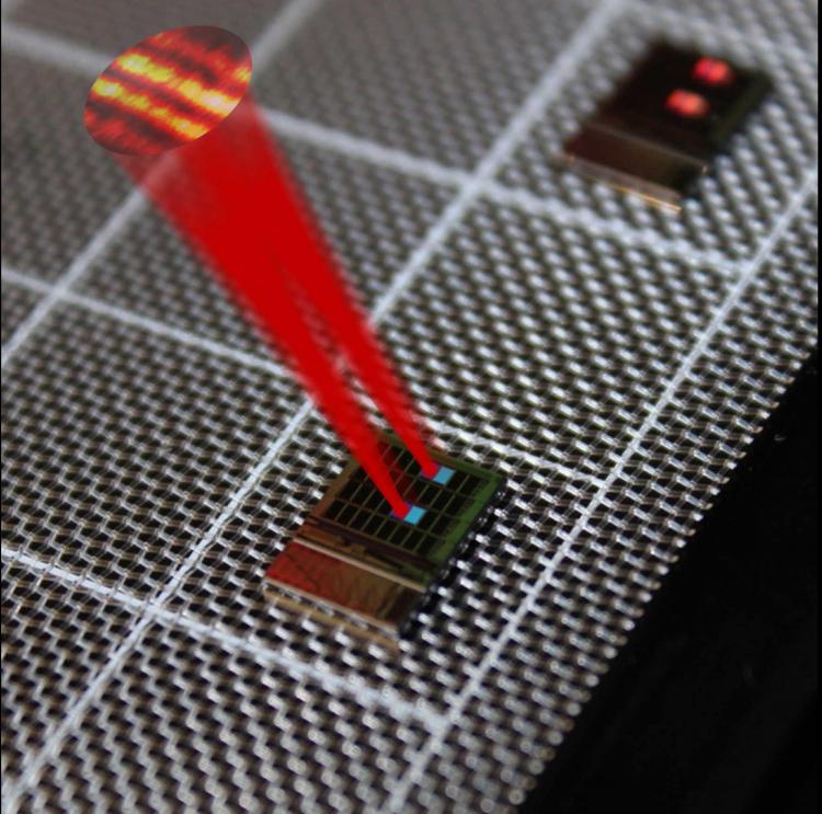 A silicon chip with a tiled array of serpentine optical phased array (SOPA) tiles. The 32 tiles in the 8-by-4 array have slightly differing grating designs, showing here two matching pairs of tiles "lighting up" at this viewing angle. Drawn superimposed are beams from two matching tiles and the far field beam interference pattern demonstrating tiled beam forming. @ Bohan Zhang and Nathan Dostart